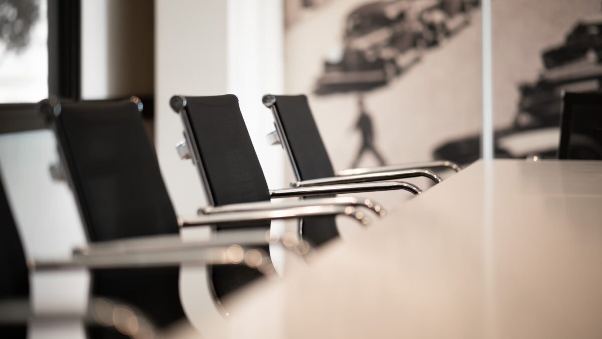 Gros plan sur des chaises de réunion noires au design élégant avec accoudoirs en métal autour d'une table blanche.