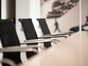 Gros plan sur des chaises de réunion noires au design élégant avec accoudoirs en métal autour d'une table blanche.