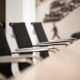 Gros plan sur des chaises de réunion noires au design élégant avec accoudoirs en métal autour d'une table blanche.